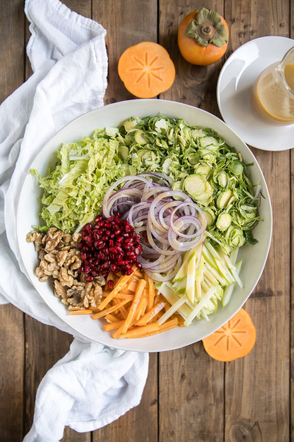 Shredded Brussels Sprout Persimmon Salad. Filled with some of falls finest like pomegranates, walnuts, pomegranates, apples, Brussels sprouts and drizzled with light dijon vinaigrette.