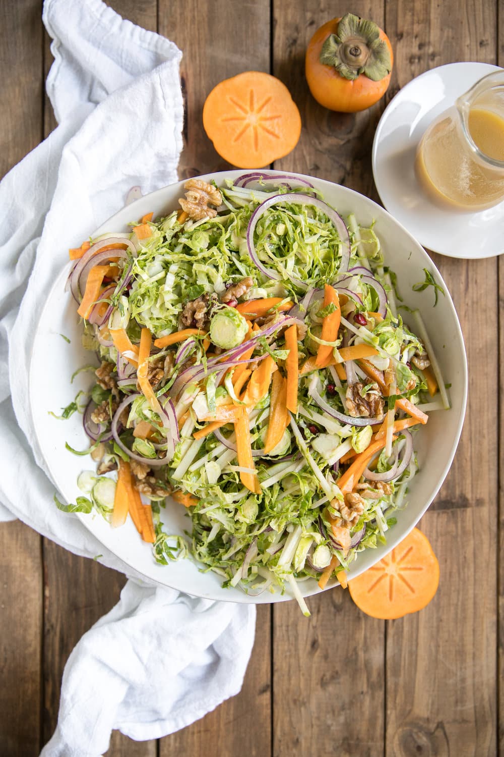 Shredded Brussels Sprout Persimmon Salad. Filled with some of falls finest like pomegranates, walnuts, pomegranates, apples, Brussels sprouts and drizzled with light dijon vinaigrette.