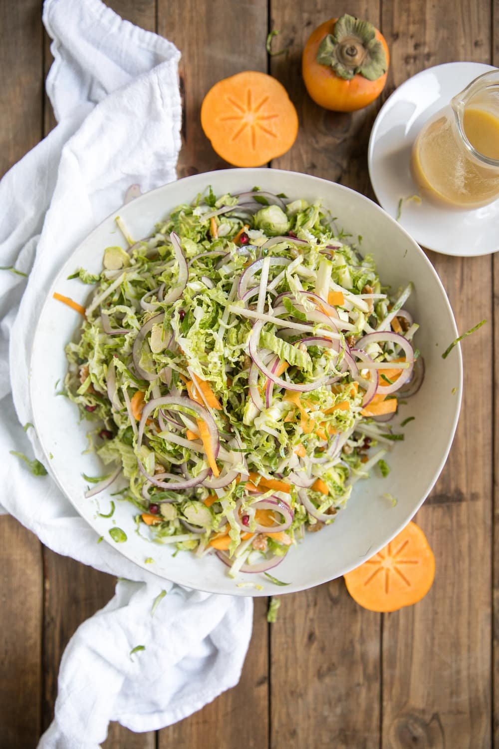 Shredded Brussels Sprout Persimmon Salad. Filled with some of falls finest like pomegranates, walnuts, pomegranates, apples, Brussels sprouts and drizzled with light dijon vinaigrette.
