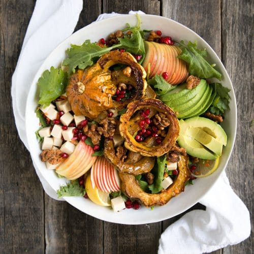 A plate of food on a wooden table, with Autumn Quinoa Apple Salad with Acorn Squash