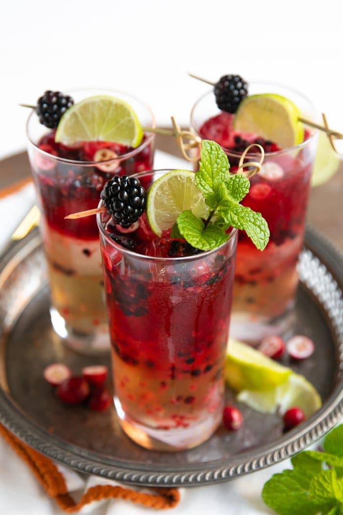 Blackberry Cranberry Moscow Mules garnished with fresh mint and lime wedges.