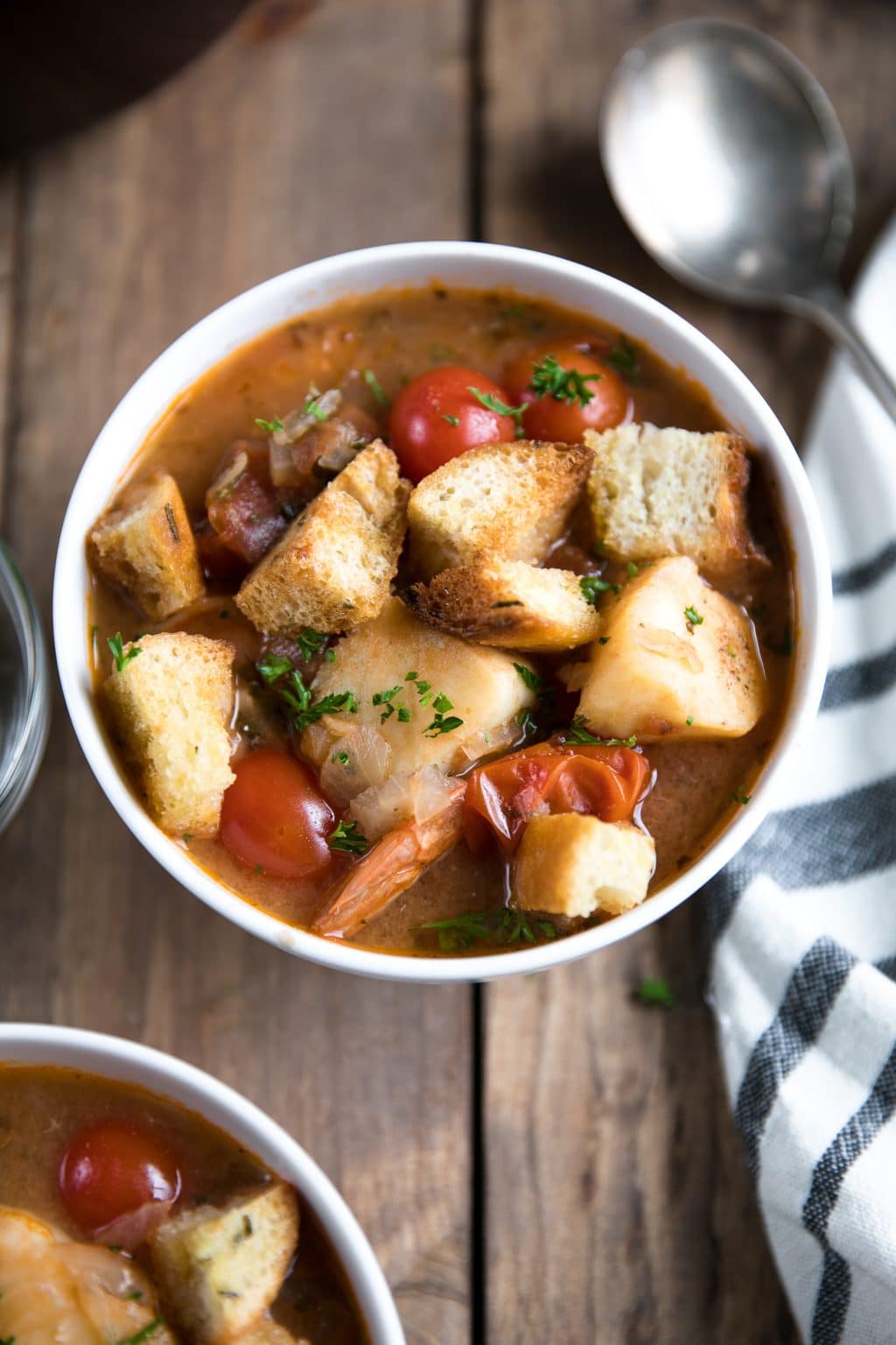 Bowls of fish soup with chunks of white fish, juicy shrimp, and a rich, comforting tomato broth.