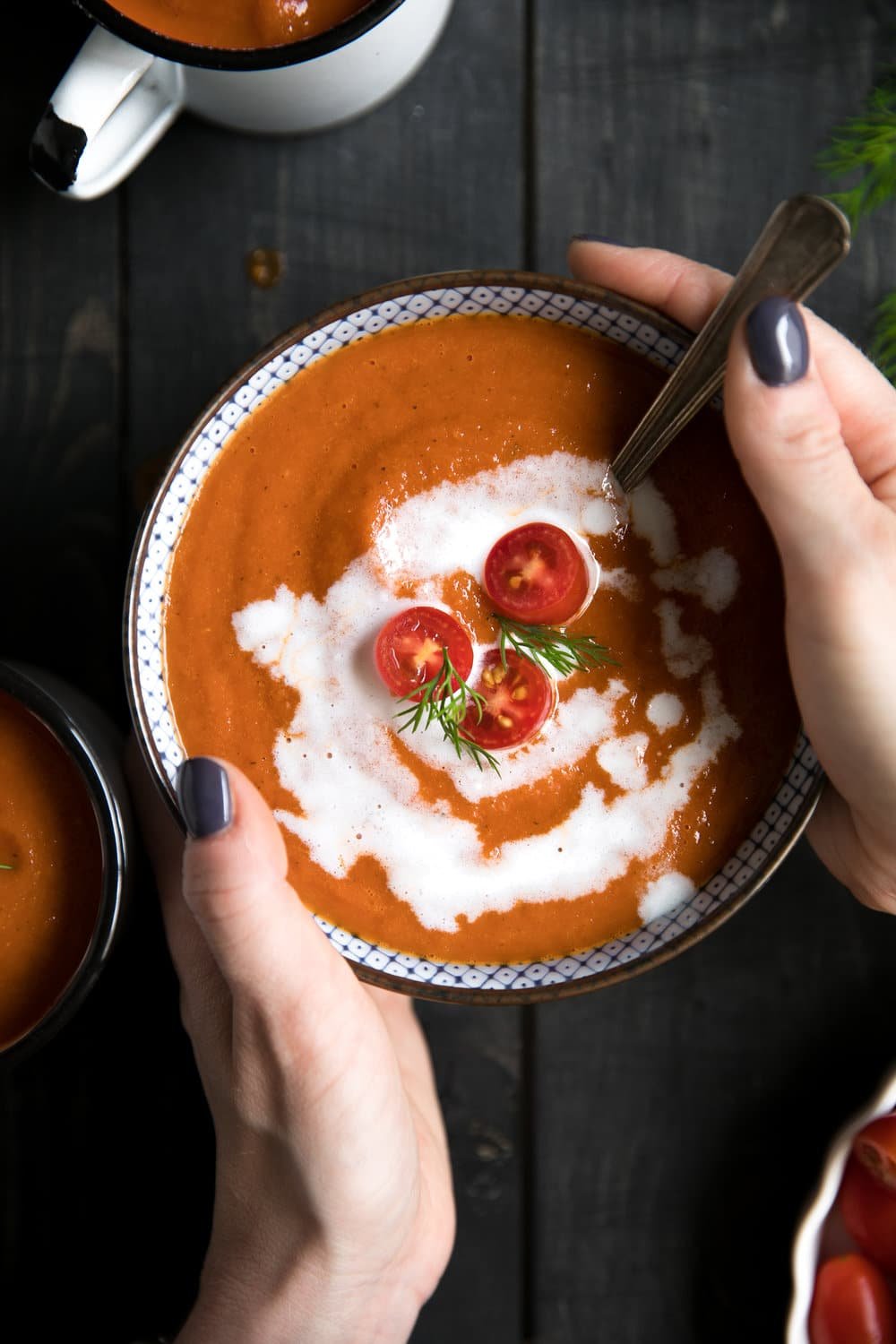 A person holding a bowl of food, with Roasted Red Pepper Soup and Tomato