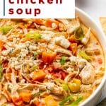 Close-up bowl of creamy buffalo chicken soup with shredded chicken, carrots, celery, buffalo sauce drizzle, crumbled blue cheese, and sliced green onions.