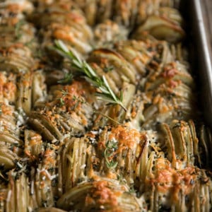 Baking pan filled with thinly sliced potatoes layered with garlic, herbs, butter, and cheese and baked until tender and crispy.