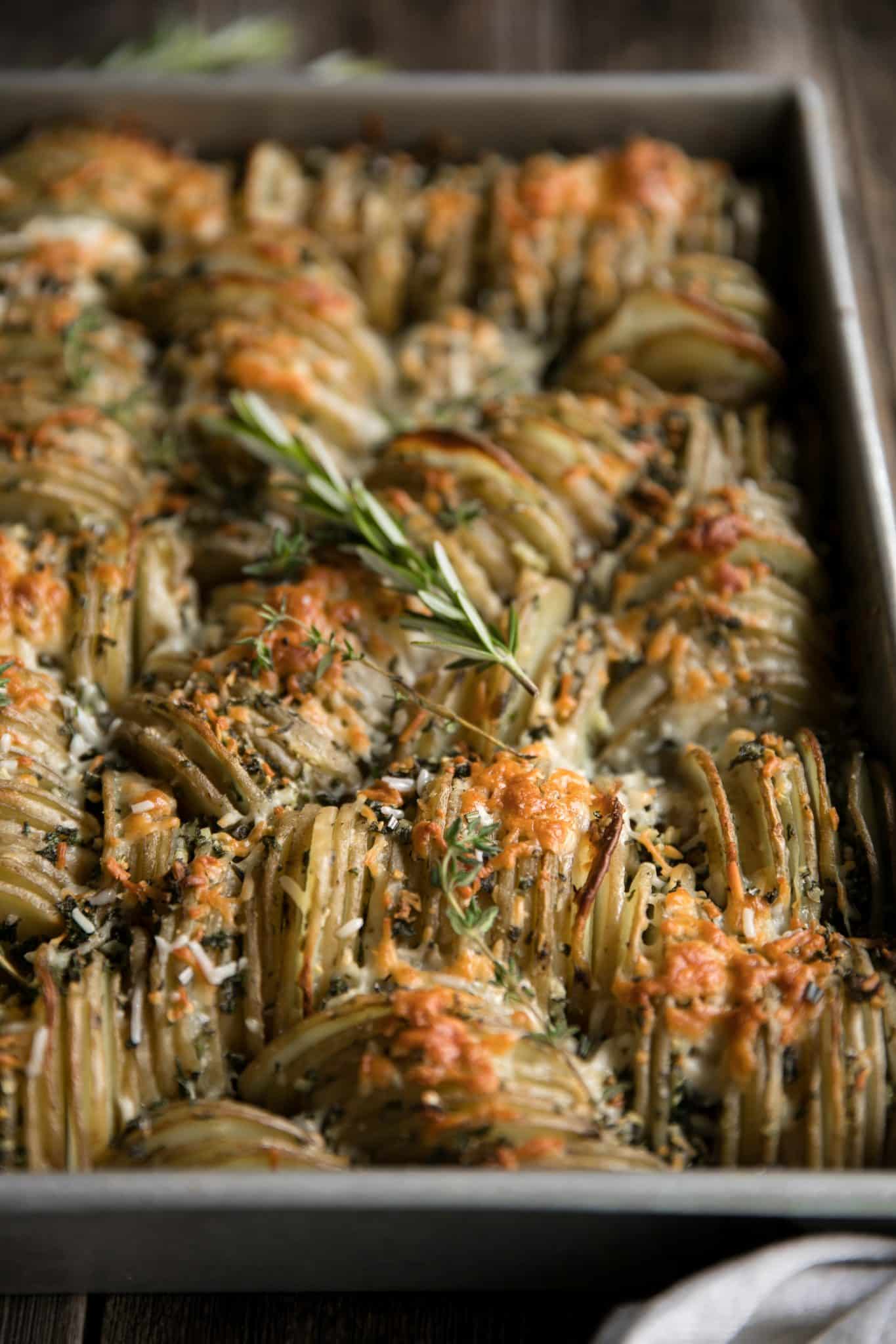Baking pan filled with thinly sliced potatoes layered with garlic, herbs, butter, and cheese and baked until tender and crispy.
