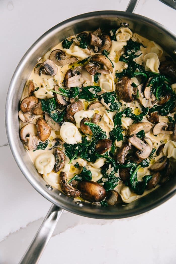 Pan filled with Creamy cheese tortellini, spinach, and mushrooms in a homemade cream sauce.