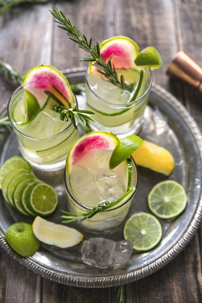 Overhead image of three glasses filled with Cucumber Rosemary Gin and Tonics garnished with watermelon radish.