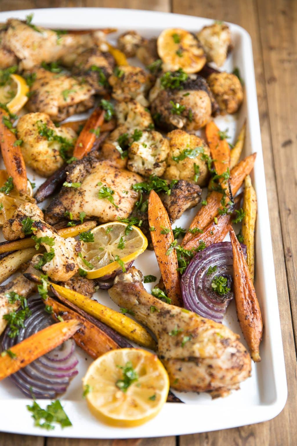 Sumac Chicken with Lemony Roasted Carrots, Cauliflower and Onion in white pan and wood background