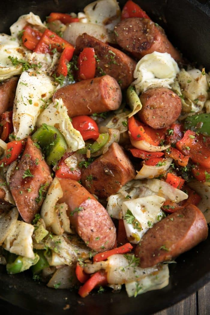 Large chunks of sauteed kielbasa, cabbage, red and green bell peppers, and onion all garnished with chopped parsley.