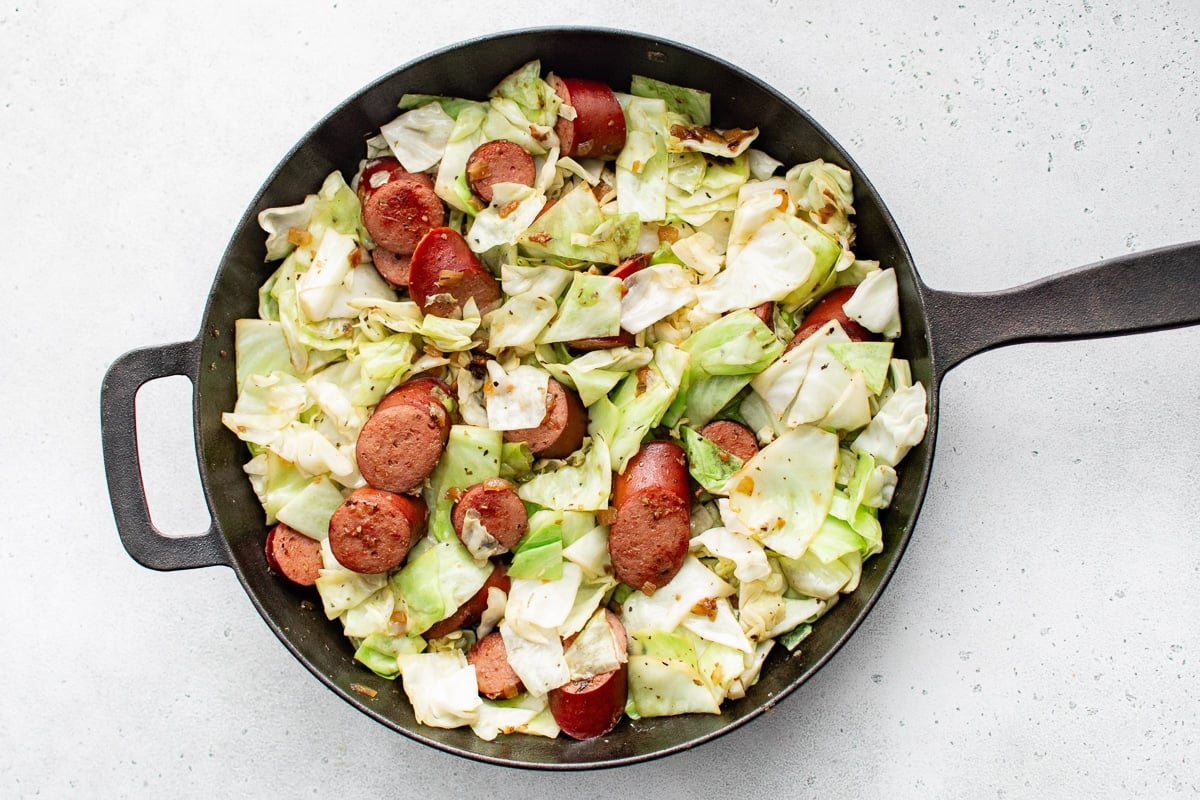 Cooked kielbasa and cabbage mixture in a skillet.