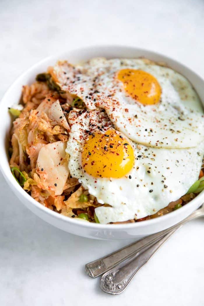 Prepared bowl filled with kimchi, cauliflower rice, and two sunny-side-up eggs