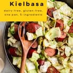 Overhead photo of a cast iron skillet filled with sizzling kielbasa sausage and sautรฉed cabbage, a quick and easy one-pan meal idea.