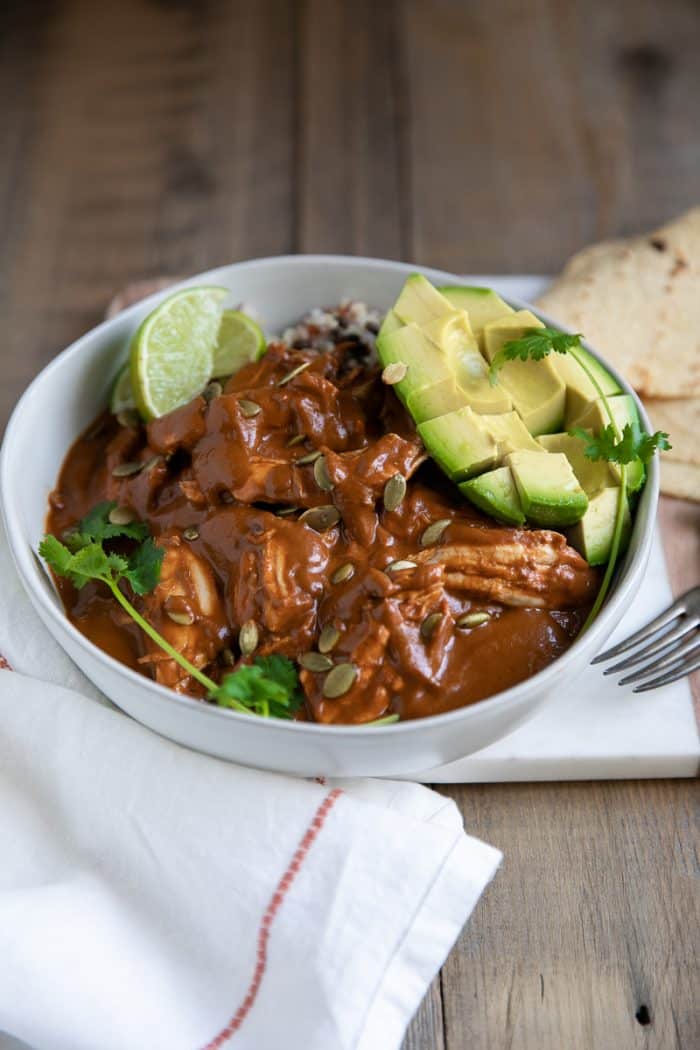 Mole sauce served with shredded chicken over rice with avocado and fresh lime.