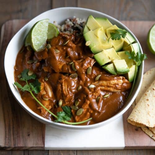 Mole sauce served with shredded chicken over rice with avocado and fresh lime.