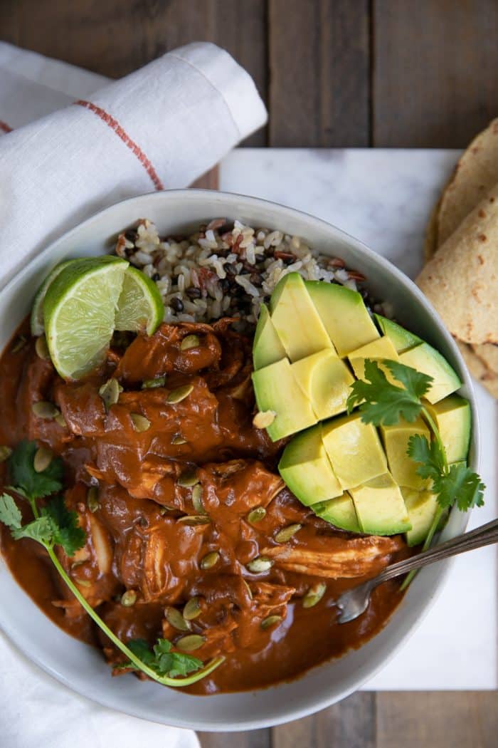 Mole sauce served with shredded chicken over rice with avocado and fresh lime.