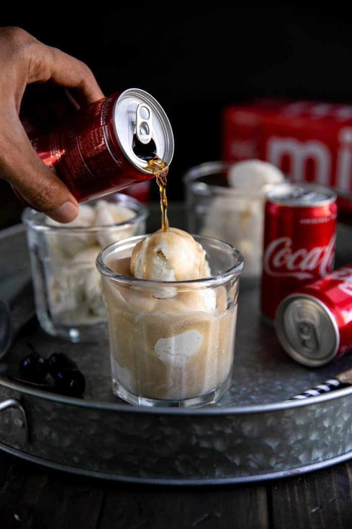 Glass with vanilla ice cream being filled with coke soda pop