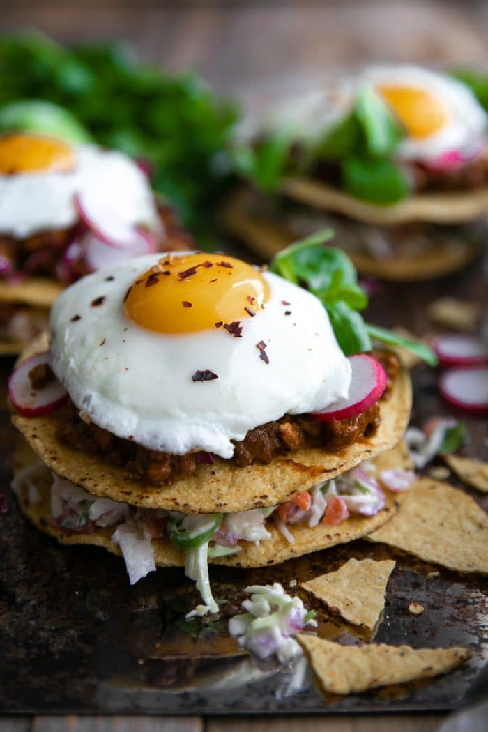 close-up of tostada stack with fried egg, coleslaw and ground turkey Molé