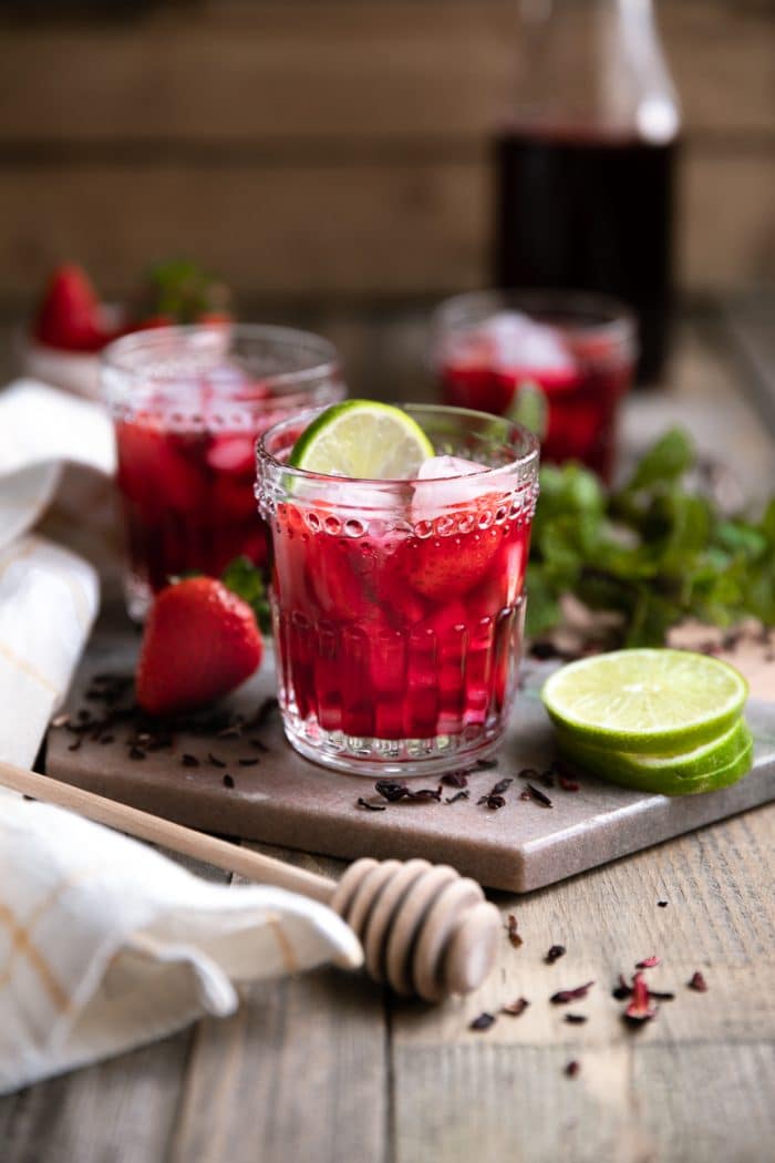 ruby red hibiscus iced tea in a clear glass garnished with lime