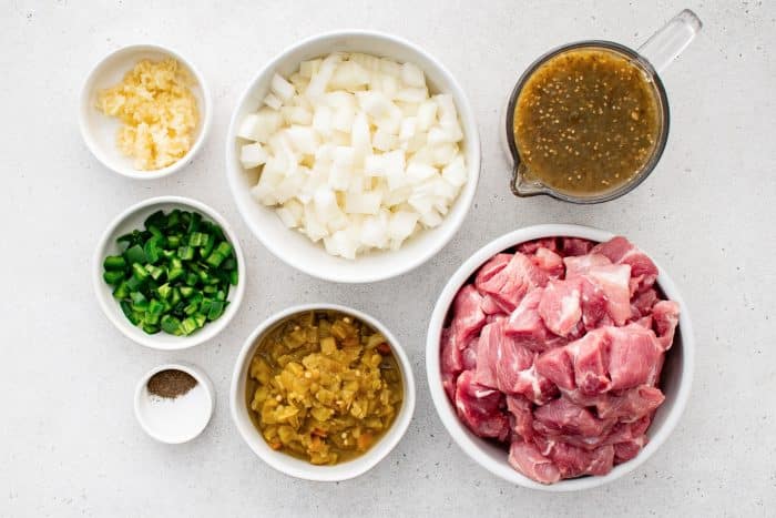All ingredients for Crock Pot Chili Verde recipe are presented in individual measuring cups and ramekins.