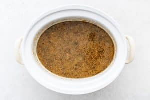 Fully cooked Crock Pot pork chile verde keeping warm in a large white slow cooker.