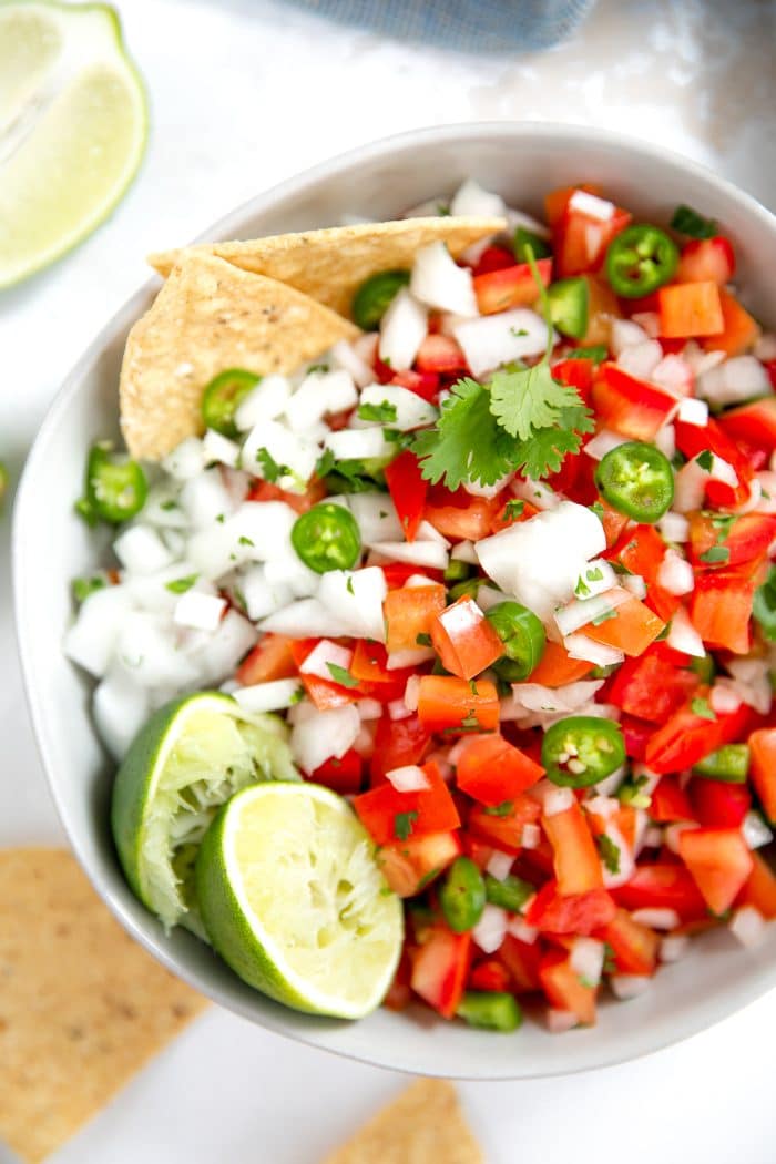 Large bowl filled with with finely diced tomatoes, onion, serrano peppers, lime juice, and salt.
