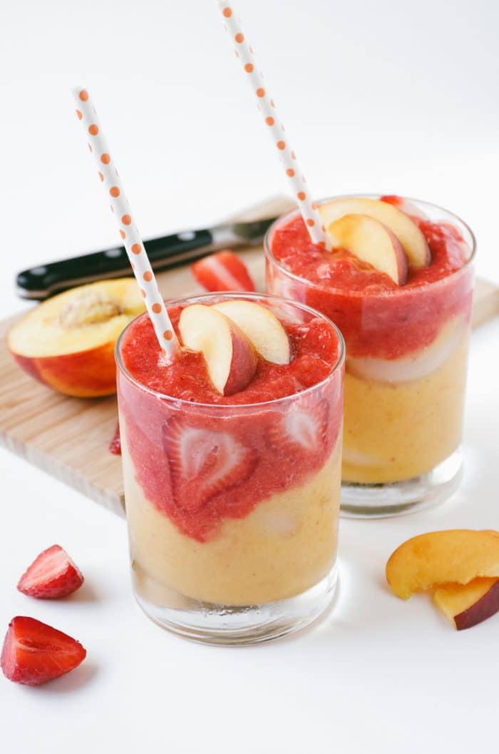 Two glasses filled with layered smoothies made with roasted fruit.
