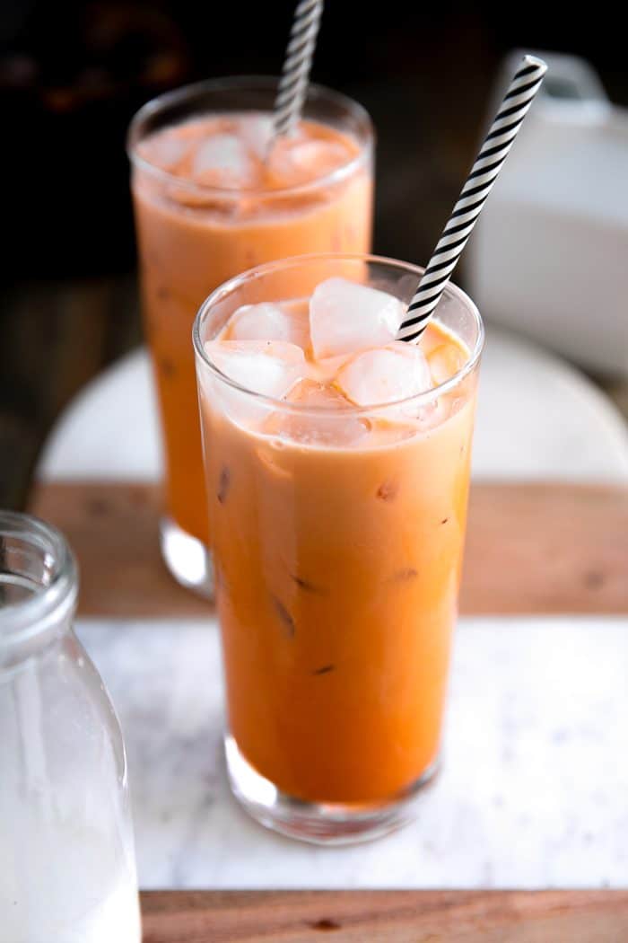 Two glasses filled with prepared and iced Thai iced tea.