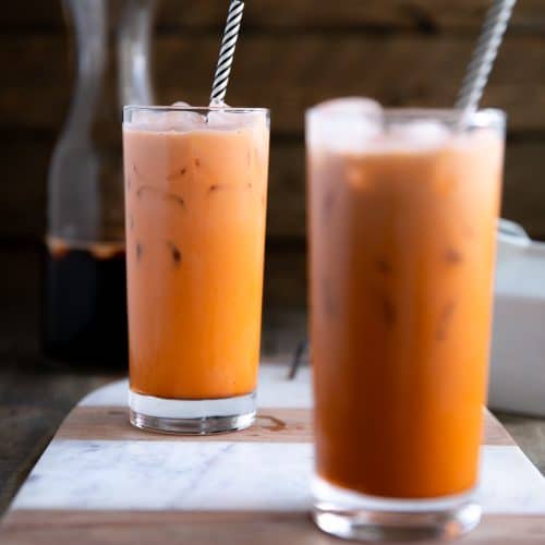 Two glasses filled with prepared and iced Thai iced tea.