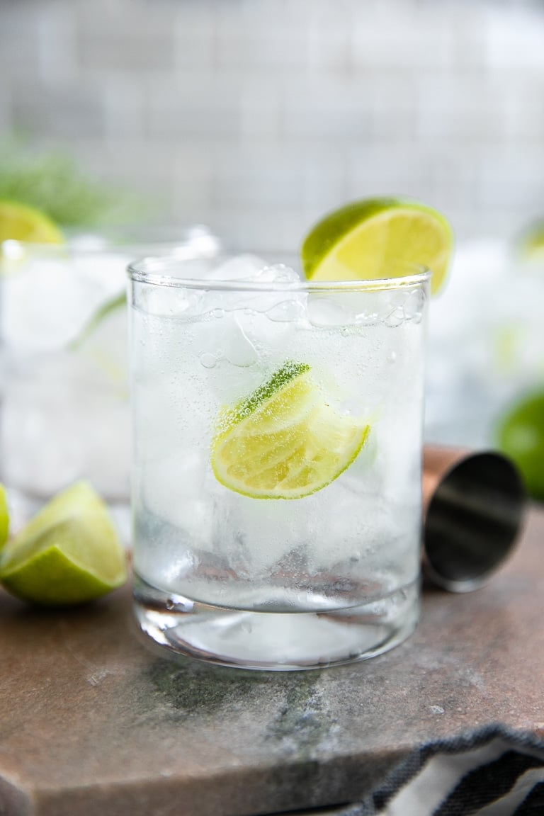 A glass gin and tonic with lime wedges