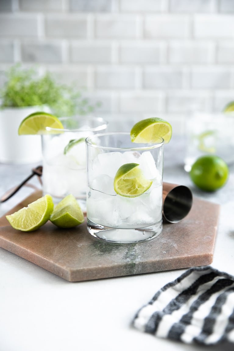 Highball glass filled with ice, one lime and gin.