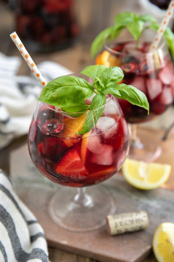 Glass filled with Strawberry Lemonade Sangria with fresh basil and and fresh cherries