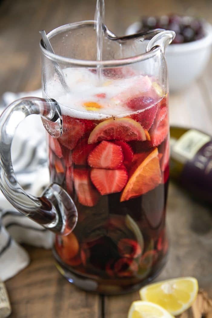 Adding the carbonated water to to the cherry strawberry lemonade sangria