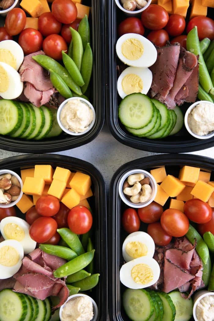 high protein snack packs filled with healthy veggies and high protein snacks including cheese, cherry tomatoes, nuts, hummus, deli meat, and eggs.