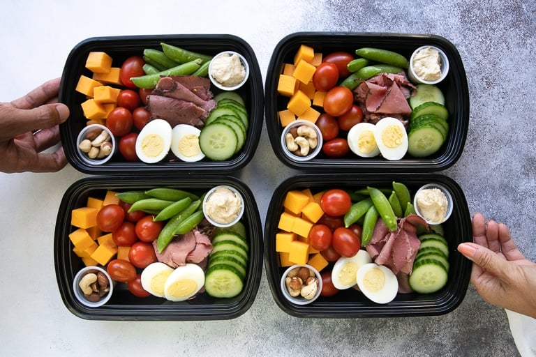 high protein snack packs filled with healthy veggies and high protein snacks including cheese, cherry tomatoes, nuts, hummus, deli meat, and eggs.