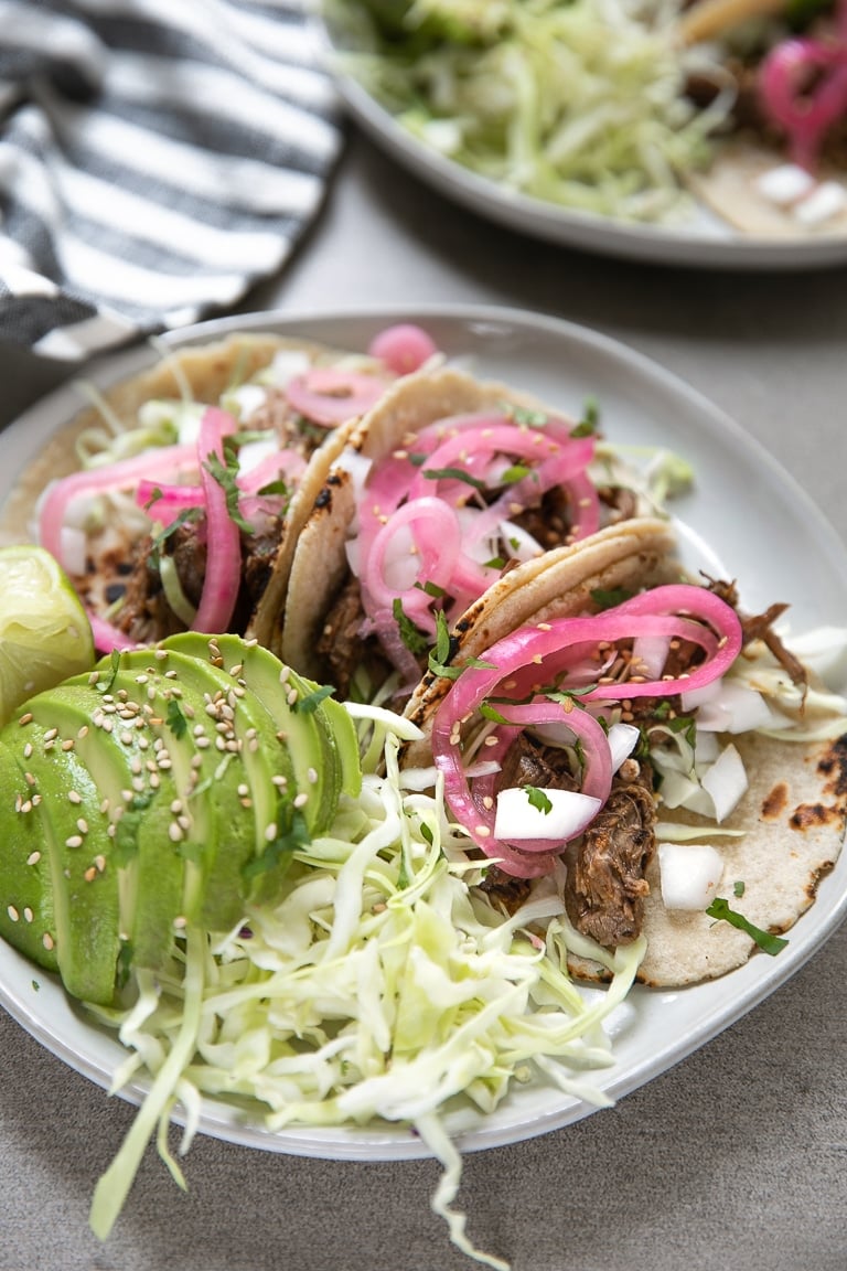 Shredded Beef Tacos with cabbage, pickled red onion, avocado, sesame seeds, and onion