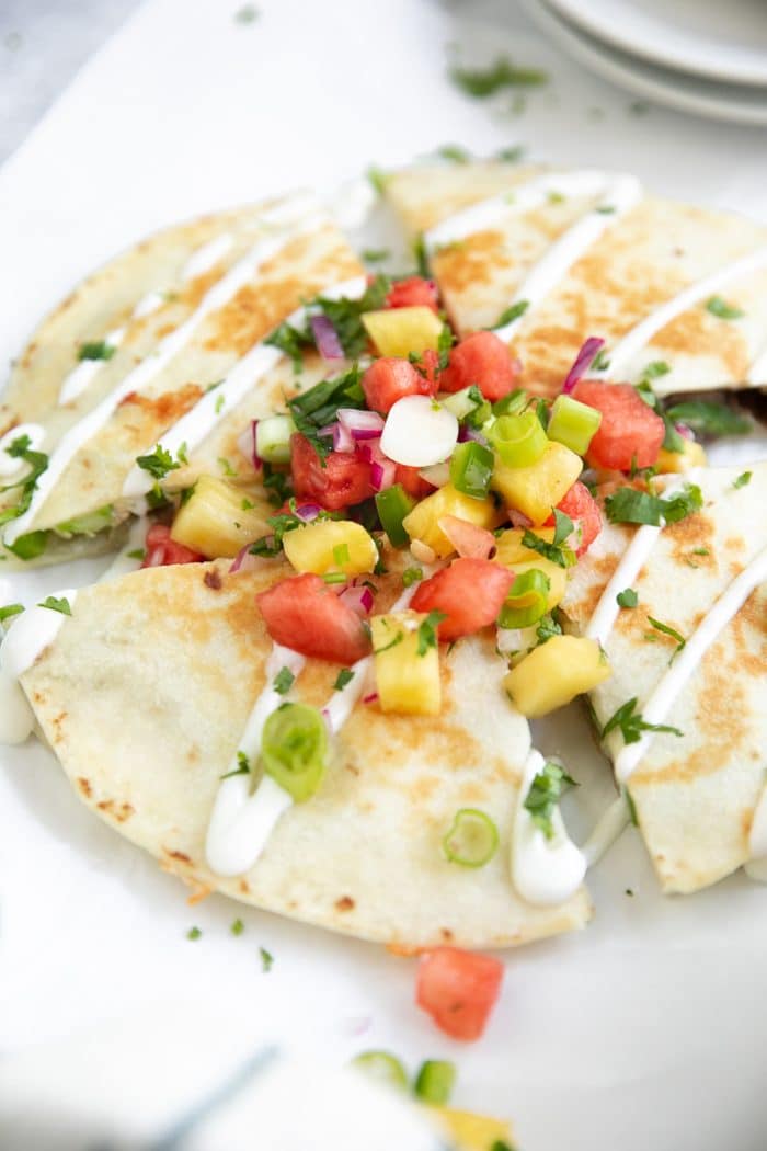 Cheese and Steak Quesadilla cut into quarters and topped with fresh watermelon pineapple salsa