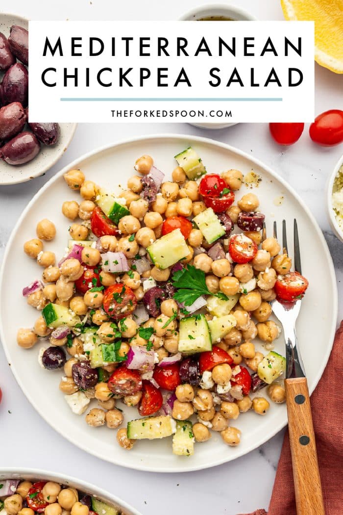 Pinterest pin image for Mediterranean Chickpea Salad with a white text box overlay reading “Mediterranean Chickpea Salad” and TheForkedSpoon.com over a plated chickpea salad with cucumber, tomatoes, red onion, Kalamata olives, feta cheese, parsley, lemon, dressing, and a rust-colored napkin.