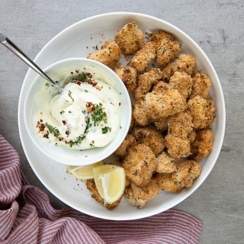 A bowl of aioli sauce on a plate, with Chicken poppers