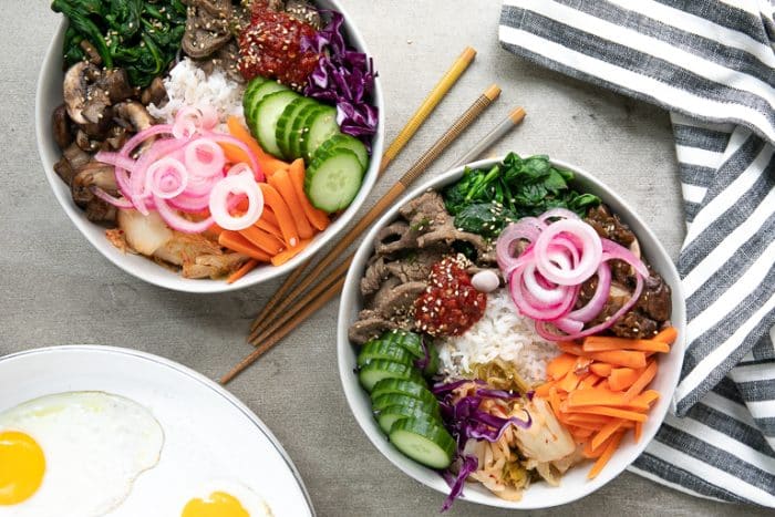 Overhead of bibimbap bowls with all the sides