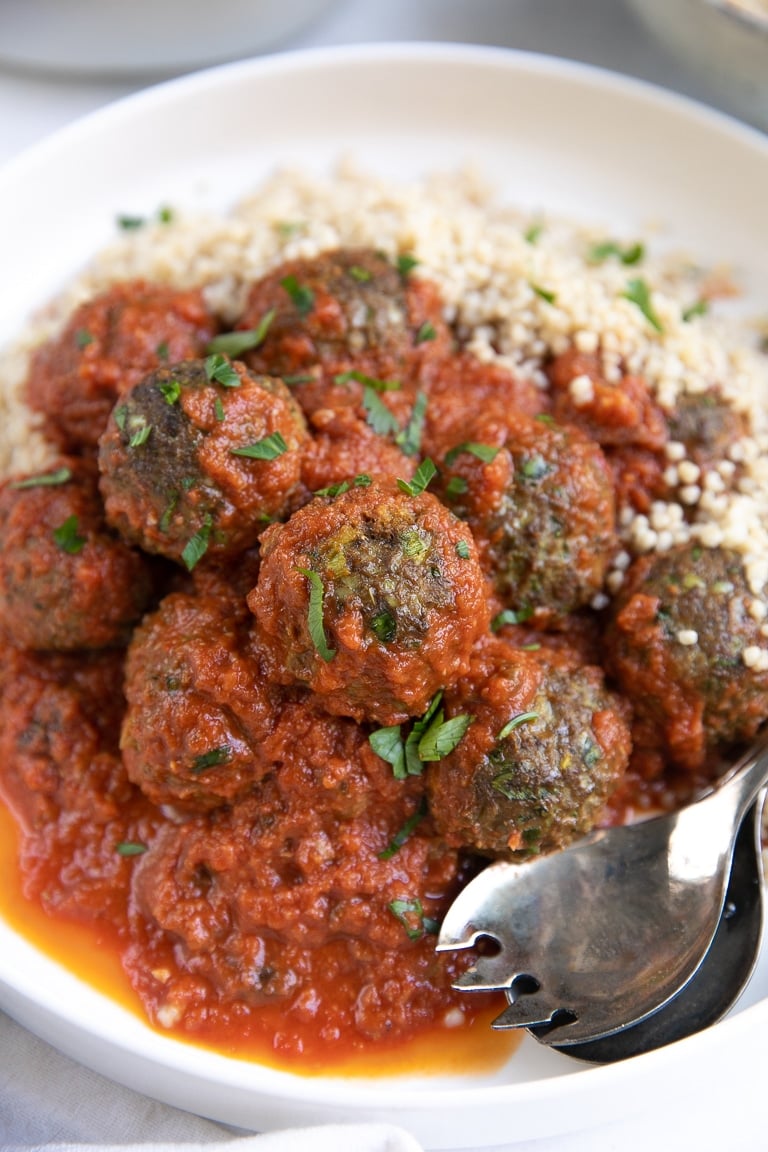 Close up images of curried lamb meatballs covered in tomato sauce