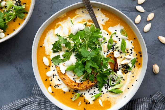squash soup with miso and coconut milk garnished with cilantro, pumpkin seeds, and green onion