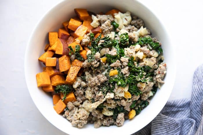 Bowl filled with cooked breakfast sausage, kale, and roasted sweet potatoes