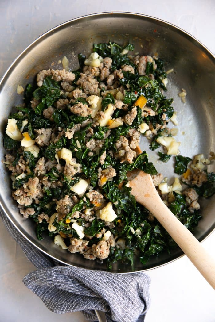 Skillet with cooked sausage, kale, and cauliflower