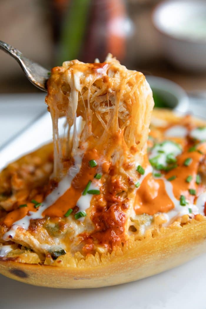 Fork pulling out a scoop of cheesy buffalo chicken spaghetti squash noodles.