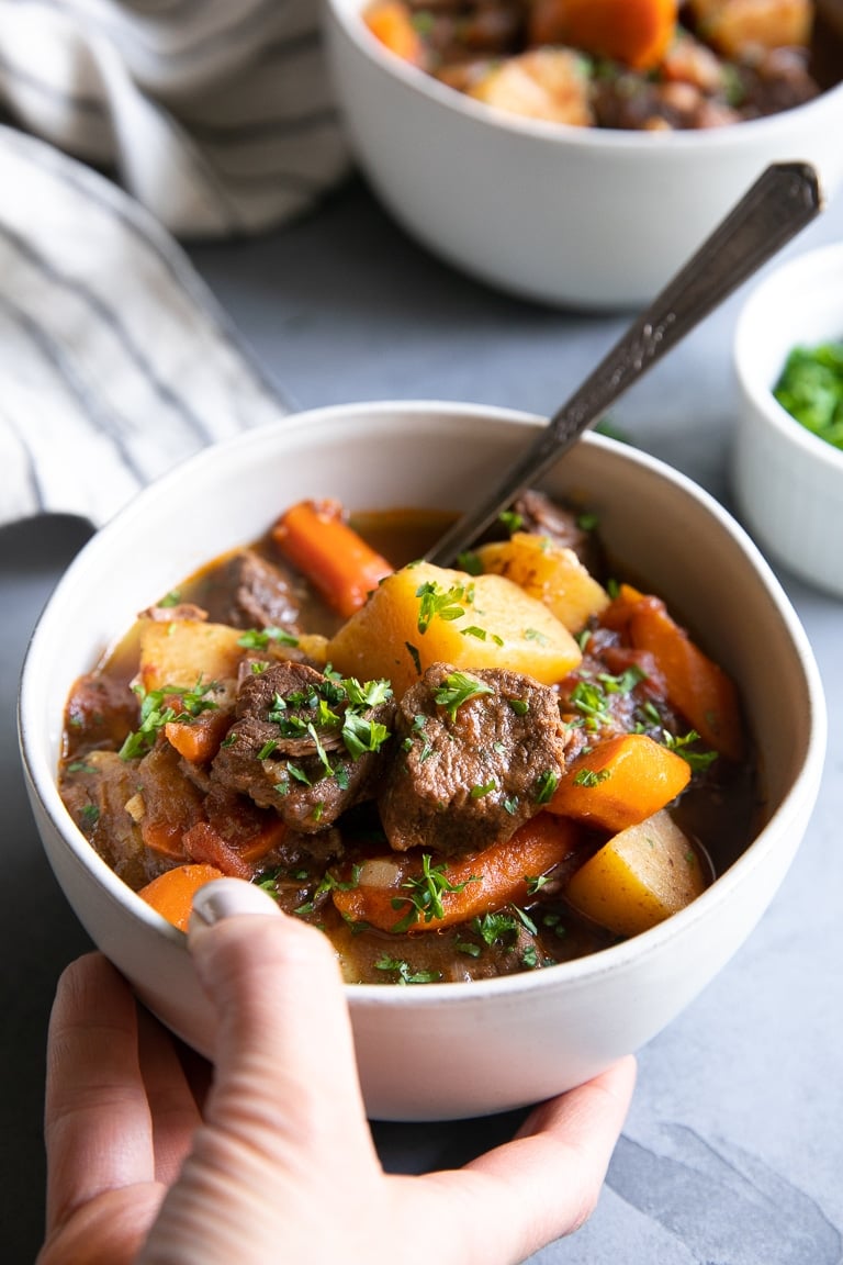 Hand holding a bowl of Instant Pot beef stew recipe