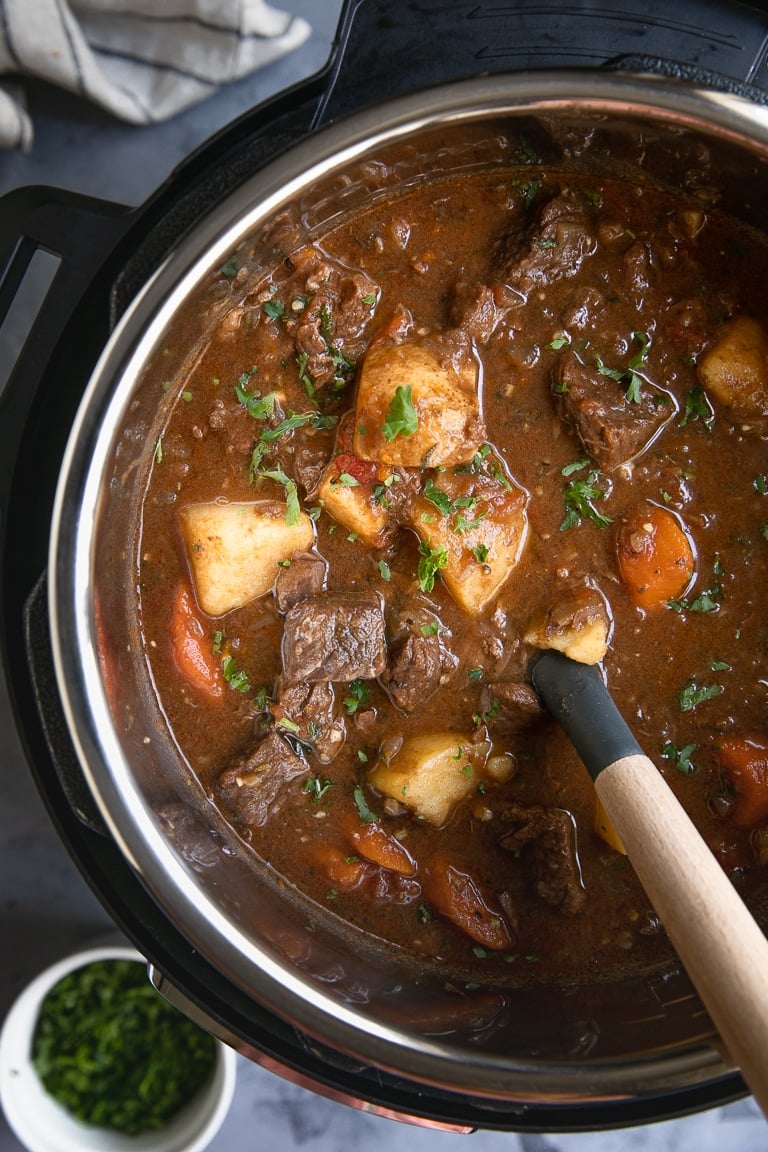 Instant Pot filled with cooked beef stew and sprinkled with chopped parsley