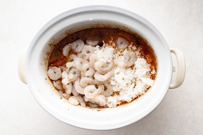 A generous layer of cooked rice and raw shrimp is added on top of the slow cooker jambalaya.