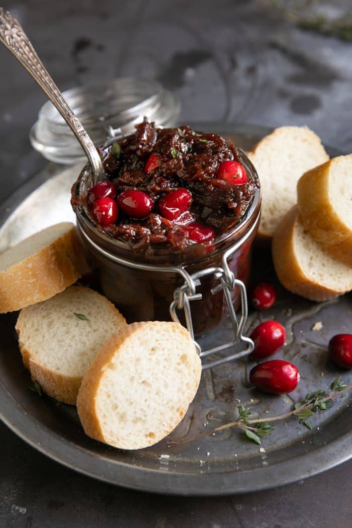 Prepared cranberry bacon jam in a small jar served with sliced baguette