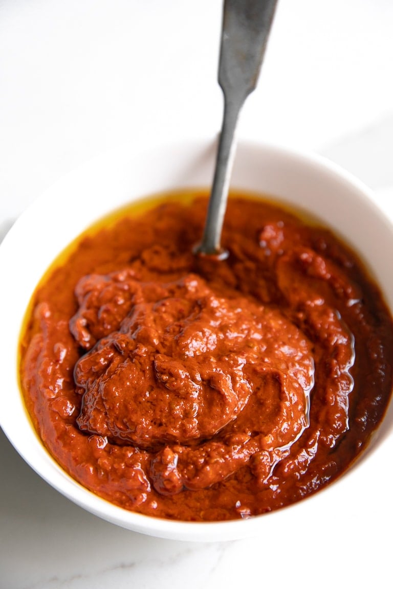 A small white bowl filled with bright red Harissa Paste